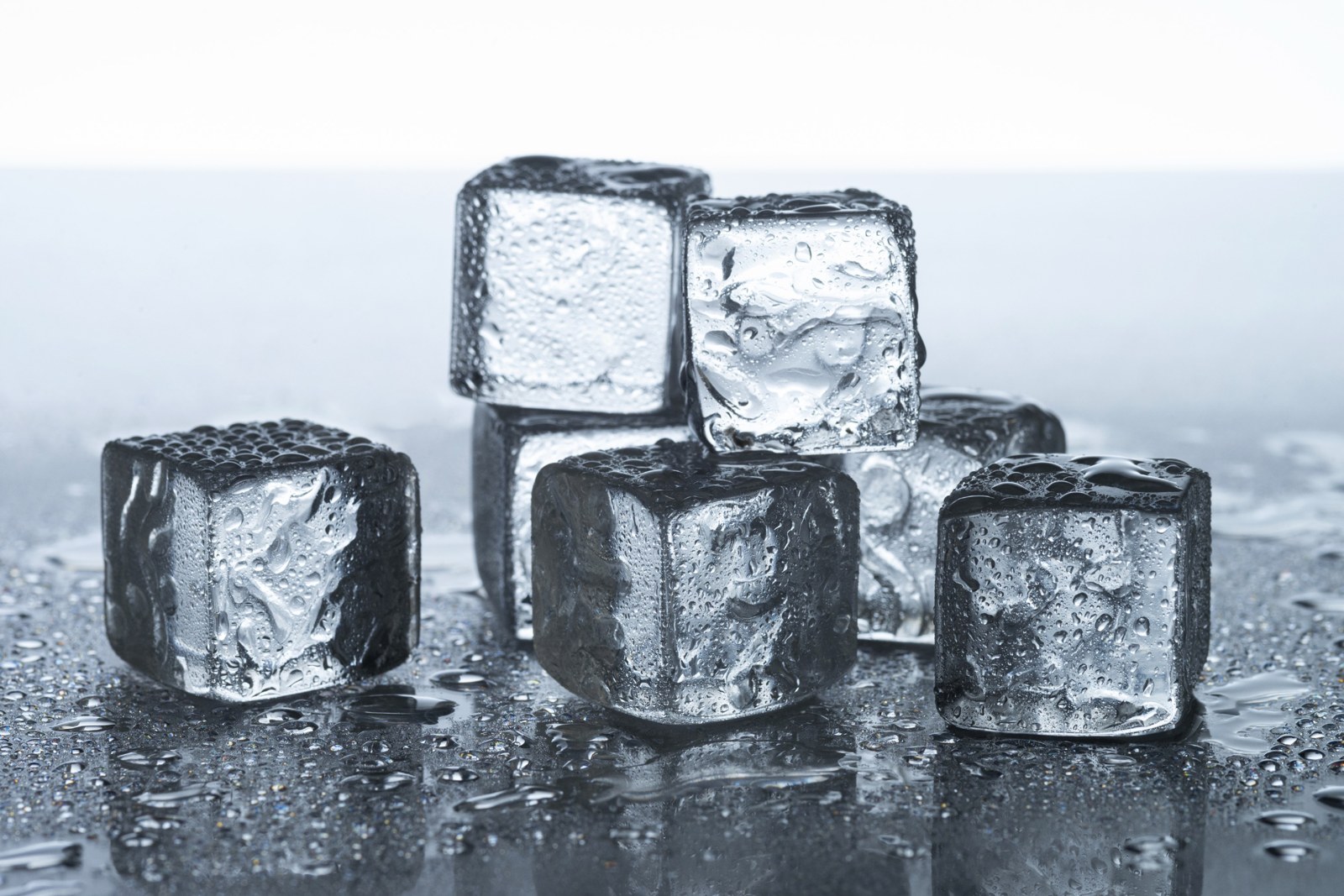 Clear ice cubes arranged on a reflective surface